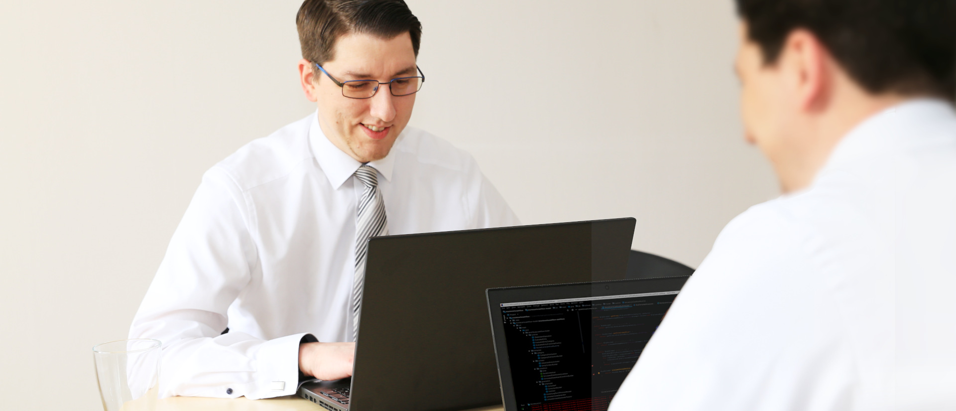 Two well dressed men working on a laptop at a table enjoying work